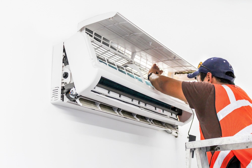 AC technician with air conditioning technician insurance installing an aircon