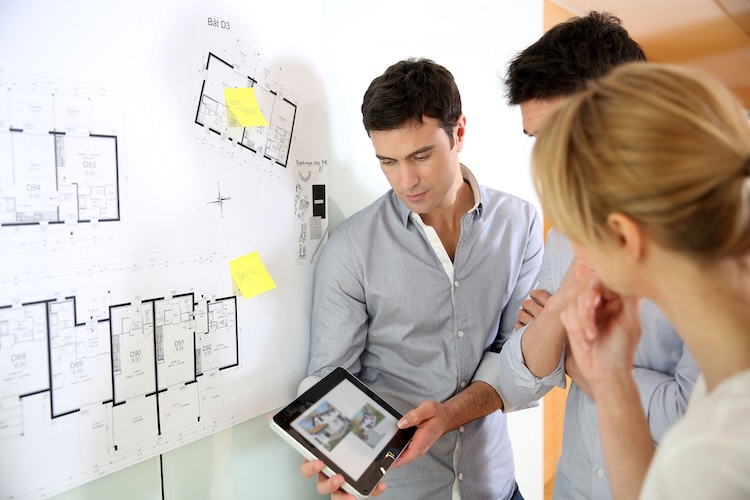 Men and women with architect and draftsmen insurance looking at plans