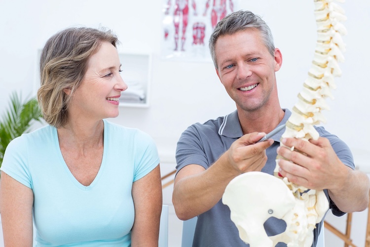 Man and woman with chiropractors insurance examining a model of the spine
