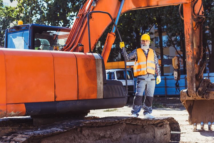 Man with earthmoving and excavation insurance standing on a dozer