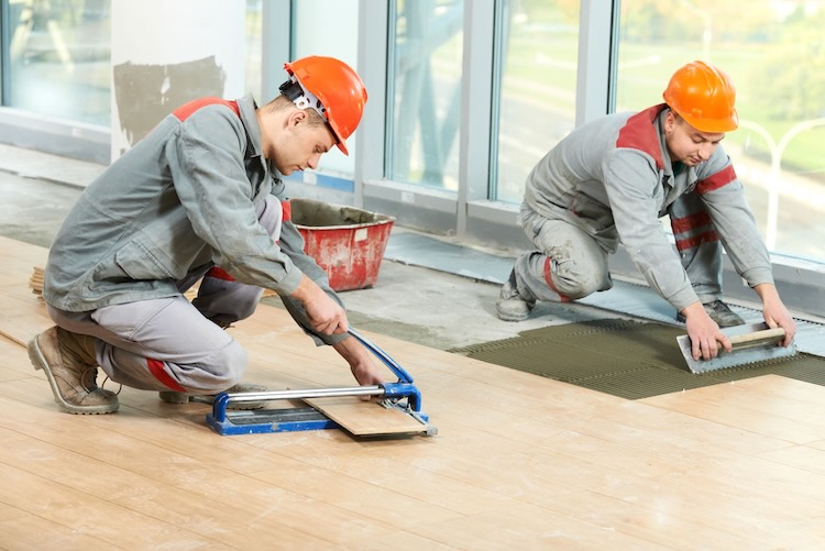 Two men with flooring insurance installing flooring