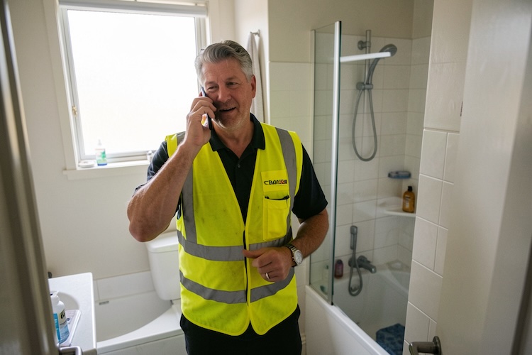 Handyman with handyman insurance on the phone in a bathroom