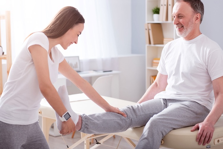 Woman with occupational therapists insurance checking a patient's leg