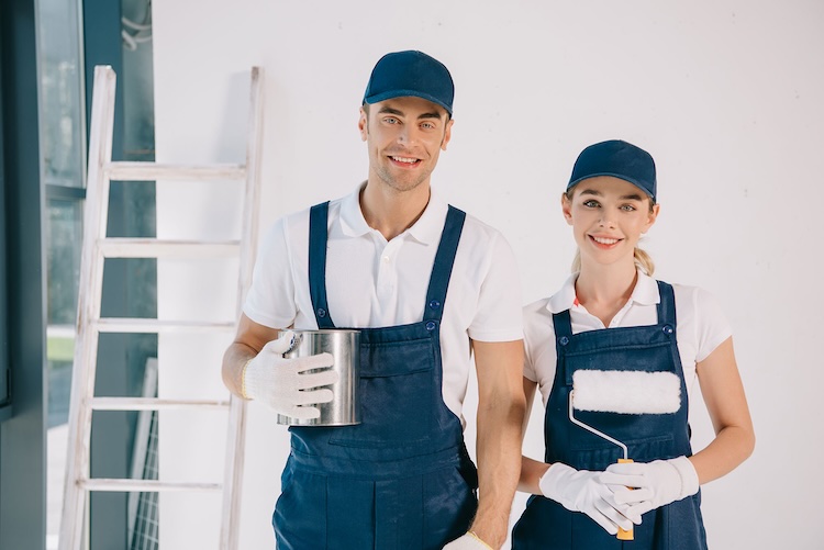 Man and woman with painters and decorators insurance holding painting tools