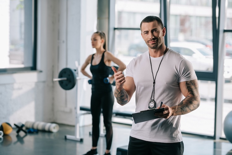 Man with personal trainer insurance instructing a woman in a gym