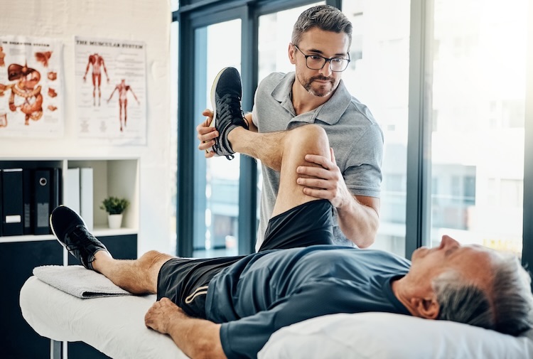 Man with physiotherapist insurance stretching a patient's leg