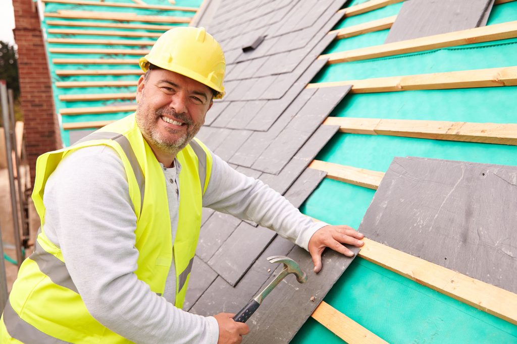 Man with roofers insurance installing shingles