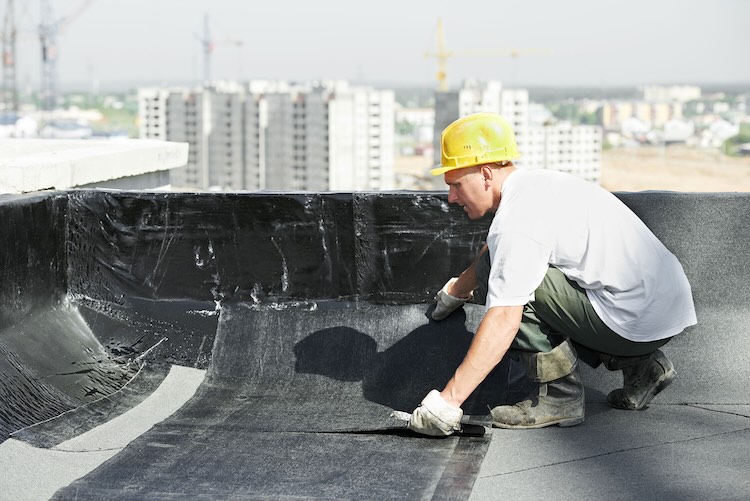 Man with waterproofing insurance waterproofing a roof