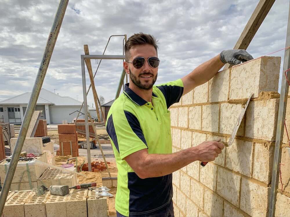 Male bricklayer laying a brick